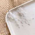 Close-up of translucent jellyfish acrylic earrings with beaded tassels on ceramic plate - White