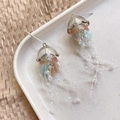 Macro detail of acrylic jellyfish earrings with pastel gradients and translucent bead tassels - Brown