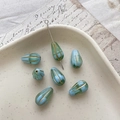 Macro detail of blue and green Czech glass teardrop beads with golden striped edges - 11# Blue Green Gold Edging