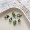 Macro detail of green teardrop glass beads with gold vertical stripes on a vintage tray - 5# Gradient Transparent Green Gold Edging