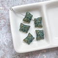 Perles papillon vintage vert bronze dans un plateau blanc pour création de bijoux - Café Transparent avec Tracé Bleu