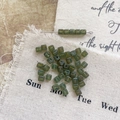Macro shot of square green glass spacer beads on rustic burlap for DIY jewelry making - Size 11