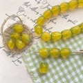 Macro detail of yellow pineapple glass beads for DIY jewelry making in a mini basket - Yellow