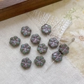 Macro detail of Czech glass flower beads with Picasso finish for DIY jewelry crafting - Green With Purple