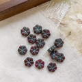 Macro view of six-petal Czech glass flower beads with vintage red and green glaze texture - Dark Red With Blue