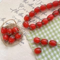 Macro shot of glass tomato beads for DIY jewelry making in a tiny woven basket - Orange Red
