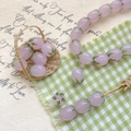 Macro detail of tulip glass beads for DIY jewelry with soft pink petals and green leaves - Pale Purple