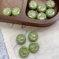 Close-up of green Czech glass daisy beads with golden floral relief for DIY jewelry - Emerald Green With Gold (8#)