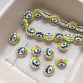 Macro detail of colorful evil eye glass beads for DIY jewelry making on white textured fabric - White