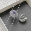Macro detail of a silver floral charm featuring an oval purple stone with double halo diamonds - Silver Purple Zircon Round