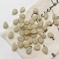 Macro shot of white leaf-shaped glass beads with gold veins for DIY jewelry making - 5-Pack / White