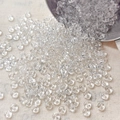 Macro view of 4mm transparent mushroom-shaped glass beads scattered on beige fabric - 10 g / Clear White