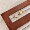 Makroansicht vergoldeter Ohrstecker-Fassungen mit Zirkonia auf einem Holzständer - 18K-Gold