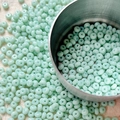 Detailed macro view of 4mm mint green seed beads in a metal bowl for DIY jewelry - 10 g / Mint Green
