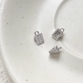 Macro shot of silver suitcase and cheese slice charms with cubic zirconia inlay details - Platinum Color Cheese