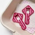 Close-up of pink striped acrylic key charms with Good Night text on cozy fabric - Rose Red