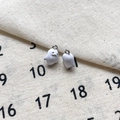 Détail de deux breloques fantômes en émail blanc avec boucles en argent sur lin - 15# Fantôme Blanc Trou Argenté
