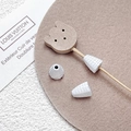 Macro shot of DIY jewelry accessories featuring a wooden bear head and textured cones - White