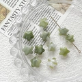 Macro detail of star-shaped green aventurine beads on a vintage glass plate - Green Crystal