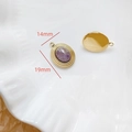 Vue macro de pendentifs ovales en pierre précieuse dorés 14mmx19mm sur un plateau - Améthyste Ovale Bordure