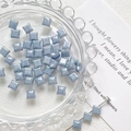 Detailed view of glaze blue star-shaped glass beads in a glass tray for DIY jewelry - Grey Blue