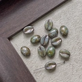 Macro detail of coffee bean shaped glass beads with a metallic reactive glaze finish - Kiln Metallic Bronze (8#)