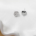 Macro detail of silver irregular hammered texture earrings on a white ceramic tray - Platinum Plated