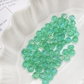 Macro view of iridescent green daisy glass beads in a white shell-shaped dish - Iridescent Green (5#)