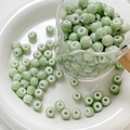 Close-up of light green glazed ceramic round beads for DIY jewelry making in a glass cup - Style 9 (8mm/10 Pieces/Pack)