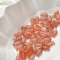 Detailed close-up of fish-shaped translucent orange Czech glass beads on a white plate - 1# Grapefruit Orange