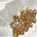 Detailed view of amber glass fish beads for jewelry making in a white shell dish - Tawny
