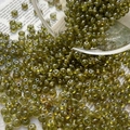 Macro view of olive green translucent glass seed beads scattered on vintage newspaper - 5# / 10 Pieces Pack