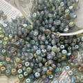 Macro view of blue frosted iridescent glass seed beads scattered on vintage newspaper - Size 9 / 10 Pieces Pack