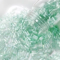 Detailed view of 6mm mint green bugle beads with AB iridescent finish scattering from bottle - 4# Mint Green Iridescent