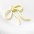 Detailopname van een roomgeel strikje met metalen ring op een wit keramisch bordje - Crèmegeel