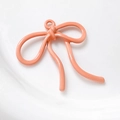 Macro-opname van 3D koraalroze emaille strikhanger met metalen ring voor DIY-sieraden maken - Koraalroze