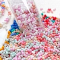Macro view of colorful resin bow-tie and dumbbell beads pouring from a glass jar - Mixed Colors