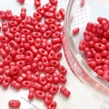 Macro view of glossy coral red peanut-shaped dual-hole glass beads for DIY jewelry - Watermelon red