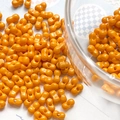 Macro detail of orange peanut-shaped double-hole beads for DIY jewelry making - Orange