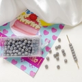Macro detail of 4mm frosted grey glass beads with storage box and beading needle tool - Gray