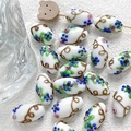 Dettaglio di perline in vetro bianco dipinte a mano con fiori blu e accenti dorati - Floreale Bianco (1#Prezzo Singolo)