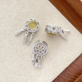 Detailed view of silver dreamcatcher pendants with yellow stones and feather tassels - White Gold