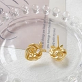 Dettaglio macro di orecchini a fiocco in oro opaco con fiori traforati su vassoio gioielli - Oro Opaco