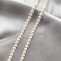 Close-up of white shell pearl strand showing glossy texture on grey satin background - Style 2 (6mm) / 6mm