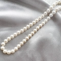 Close-up of glossy white shell pearls on silver silk fabric showing luxury texture - 3# (8mm) / 8mm