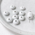 Macro shot of white ceramic flat round beads for DIY jewelry making on a tray - White Series (1#)