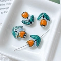 Macro detail of hand-painted orange tulip ceramic beads for DIY jewelry making - Orange
