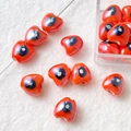 Macro shot of red heart-shaped ceramic beads with hand-painted patterns for DIY jewelry - Heart Evil Eye / Dark Red