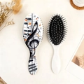 Flat lay of piano key pattern hairbrushes with music note design on warm background - Piano Black And White Style