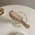 Dettaglio del pettine in acetato con trama marmorea appoggiato su un bicchiere - Color Farina d'Avena